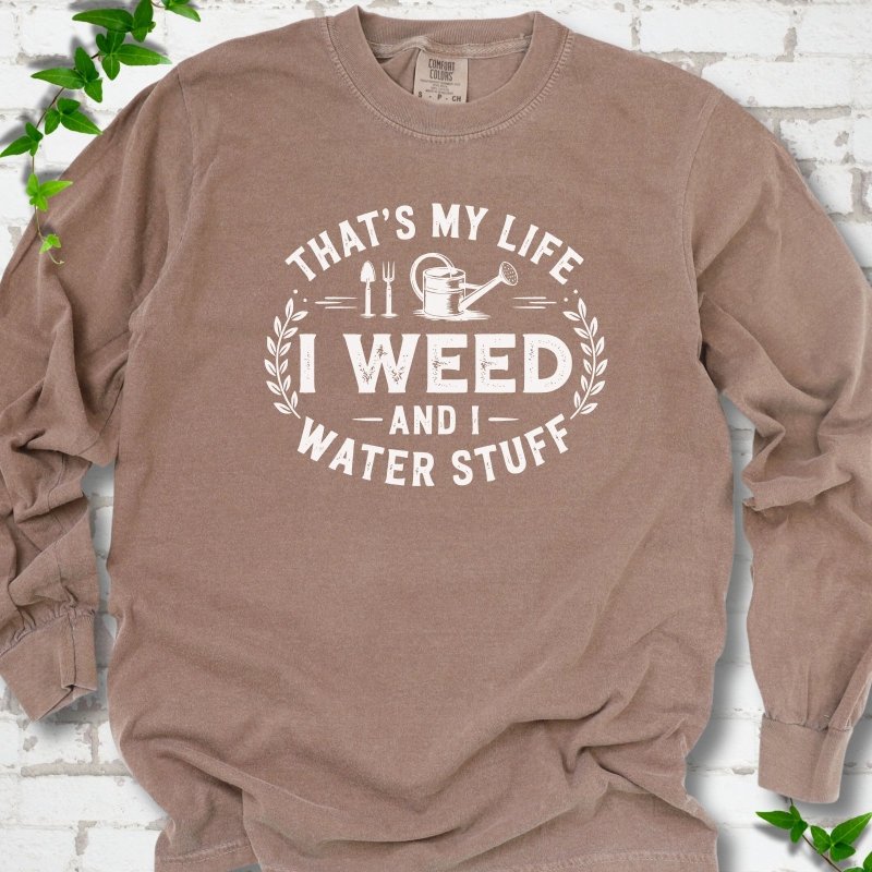 Espresso Comfort Colors® long sleeve T-shirt flat lay featuring That's My Life I Weed and I Water Stuff text with a watering can and garden tools.