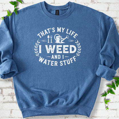 Indigo Blue Gildan® 18000 crewneck sweatshirt flat lay with garden tools and the words “That’s my life, I weed and I water stuff.”