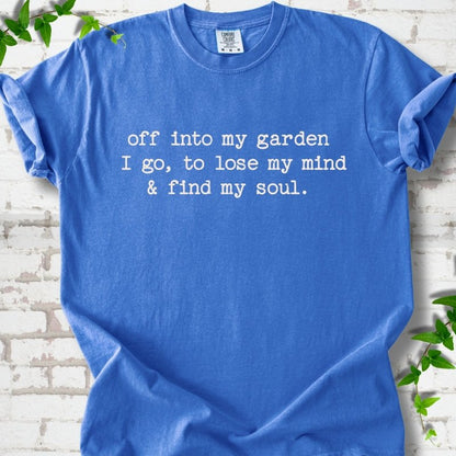 Flo Blue Comfort Colors® short sleeve T-shirt flat lay with white text reading "Off into my garden I go, to lose my mind and find my soul"