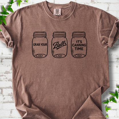 Espresso T-shirt flat lay with black line-art illustrations of three mason jars in a row, the first reading "Grab your", the middle with "Balls" in script and the last reading "It's canning time", on white brick with ivy sprigs.