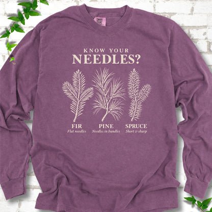 Berry long sleeve tee laid flat, showing cream fir, pine and spruce needle illustrations beneath "Know Your Needles?" with identification labels.