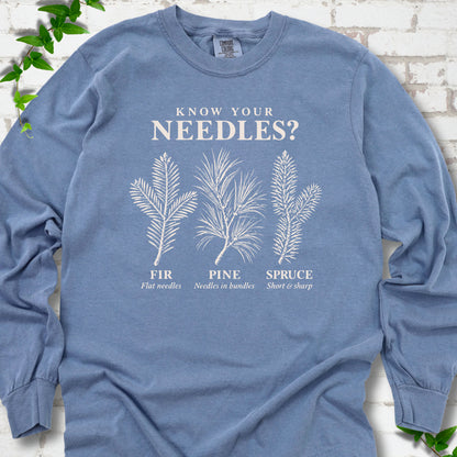 Blue Jean long sleeve tee laid flat, showing cream fir, pine and spruce needle illustrations beneath "Know Your Needles?" with identification labels.