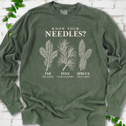 Hemp long sleeve tee laid flat, showing cream fir, pine and spruce needle illustrations beneath "Know Your Needles?" with identification labels.