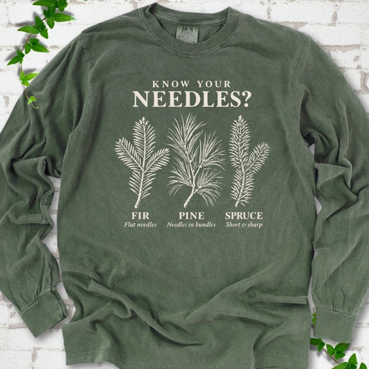 Hemp long sleeve tee laid flat, showing cream fir, pine and spruce needle illustrations beneath "Know Your Needles?" with identification labels.