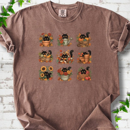 Front flat lay of a Espresso short sleeve T-shirt with a nine-panel grid of black cats among fall garden flowers, pots and leaves, on white brick with green leafy sprigs.