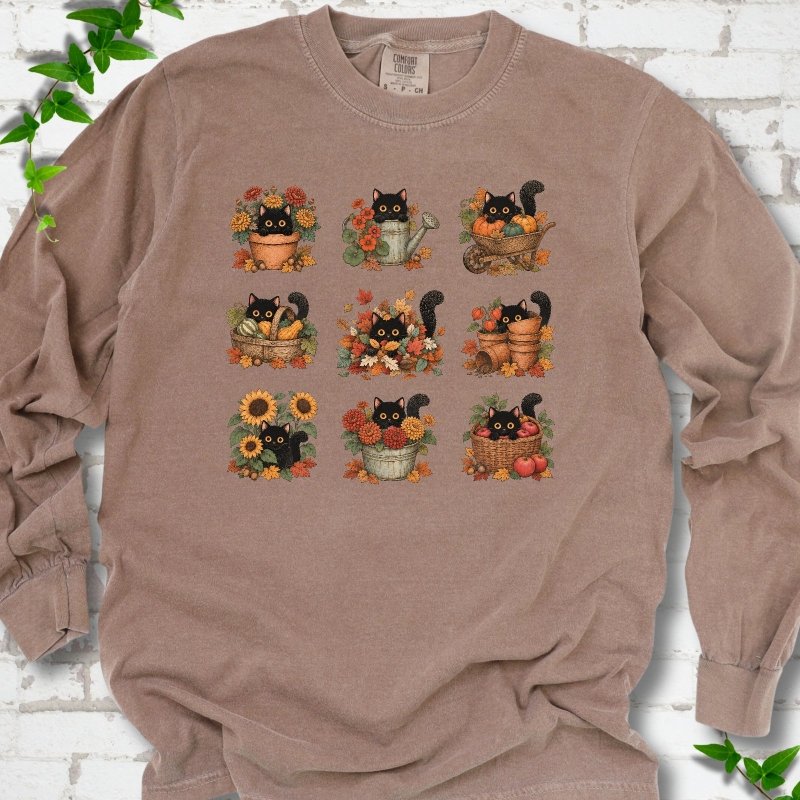 Front flat lay of a Espresso long sleeve T-shirt with a nine-panel grid of black cats among fall garden flowers, pots and leaves, on white brick with green leafy sprigs.