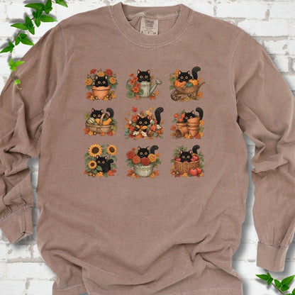 Front flat lay of a Espresso long sleeve T-shirt with a nine-panel grid of black cats among fall garden flowers, pots and leaves, on white brick with green leafy sprigs.