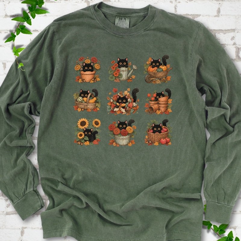 Front flat lay of a Hemp long sleeve T-shirt with a nine-panel grid of black cats among fall garden flowers, pots and leaves, on white brick with green leafy sprigs.