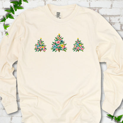 Ivory long-sleeve T-shirt laid flat on white brick with three flower-filled trees centered on the front.