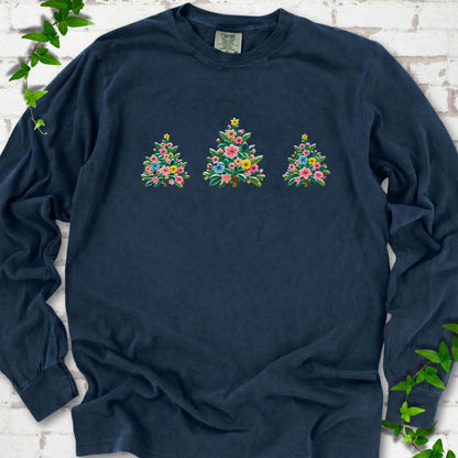 Midnight long-sleeve T-shirt laid flat on white brick with three flower-filled trees centered on the front.