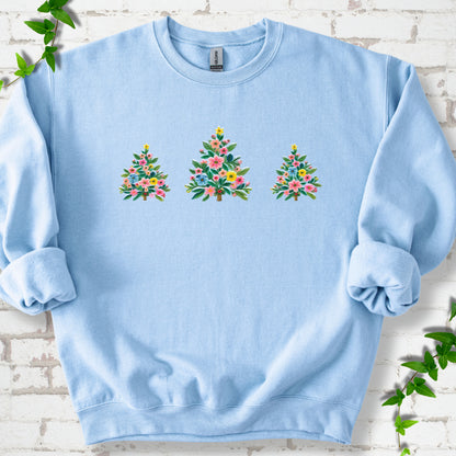 Light Blue crewneck sweatshirt laid flat on white brick with three flower-filled trees centered on the front.