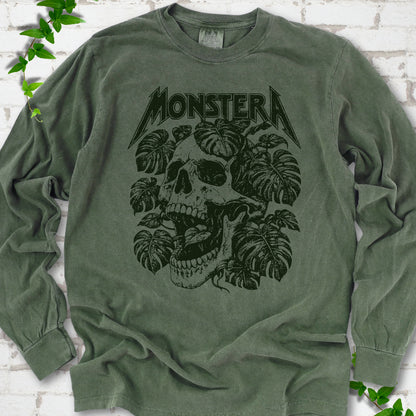 Hemp Comfort Colors® long sleeve T-shirt with distressed skull and monstera leaves beneath MONSTERA lettering, flat lay on white brick.