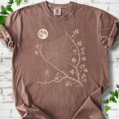Espresso Comfort Colors® T-shirt flat lay featuring a cream moon, spider web, berry branches and hanging spider design.