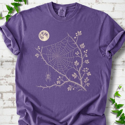 Grape Comfort Colors® T-shirt flat lay featuring a cream moon, spider web, berry branches and hanging spider design.
