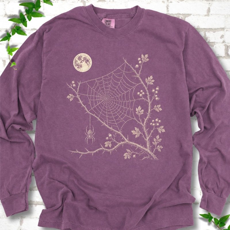 Berry Comfort Colors® long sleeve T-shirt flat lay featuring a cream moon, spider web, berry branches and hanging spider design.