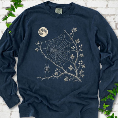 Midnight Comfort Colors® long sleeve T-shirt flat lay featuring a cream moon, spider web, berry branches and hanging spider design.
