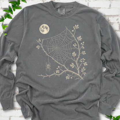 Pepper Comfort Colors® long sleeve T-shirt flat lay featuring a cream moon, spider web, berry branches and hanging spider design.