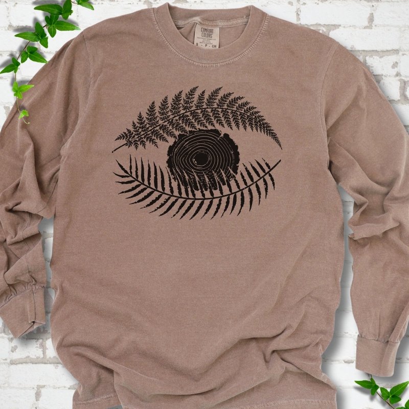 Espresso Comfort Colors® long sleeve T-shirt flat lay featuring a black botanical eye formed by fern fronds and a tree-ring centre.