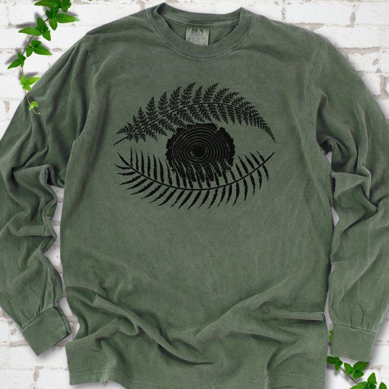 Hemp Comfort Colors® long sleeve T-shirt flat lay featuring a black botanical eye formed by fern fronds and a tree-ring centre.