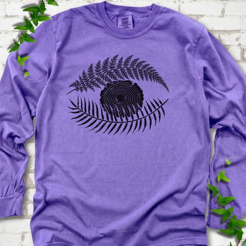 Violet Comfort Colors® long sleeve T-shirt flat lay featuring a black botanical eye formed by fern fronds and a tree-ring centre.