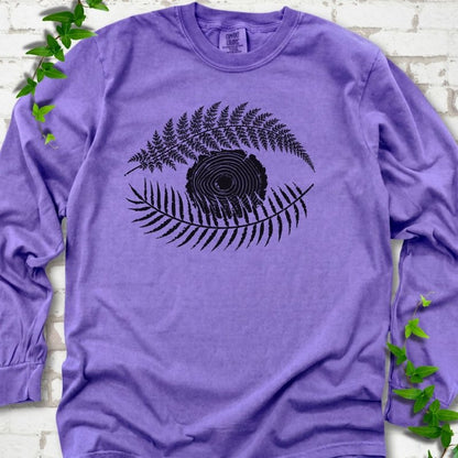Violet Comfort Colors® long sleeve T-shirt flat lay featuring a black botanical eye formed by fern fronds and a tree-ring centre.