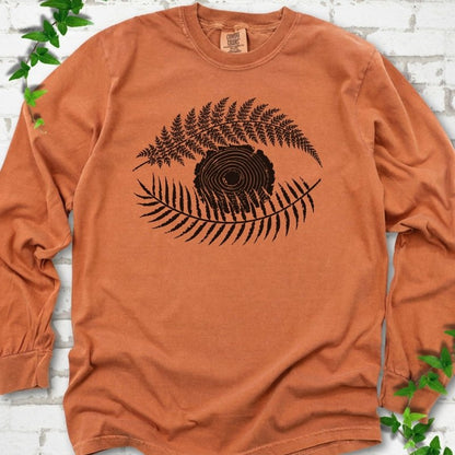 Yam Comfort Colors® long sleeve T-shirt flat lay featuring a black botanical eye formed by fern fronds and a tree-ring centre.