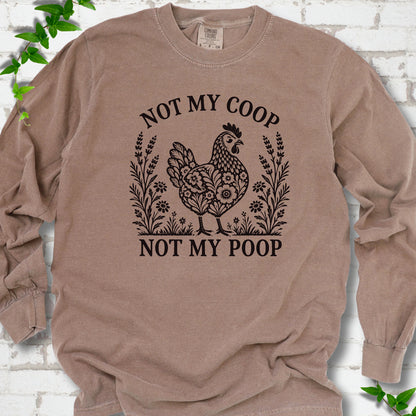Espresso long sleeve T-shirt flat lay with a dark brown folk-art hen surrounded by wildflowers and lavender, "Not my coop" arched above and "Not my poop" below, on white brick with ivy.