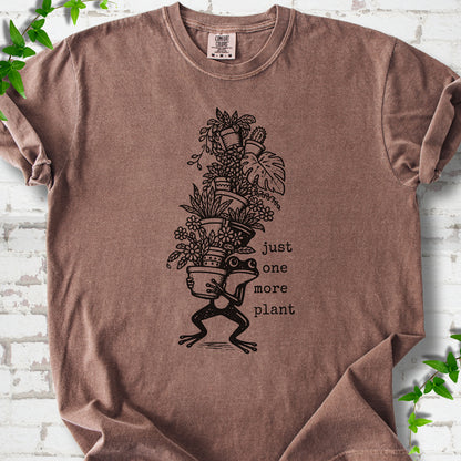 Espresso Comfort Colors® T-shirt flat lay featuring a frog carrying a tall stack of houseplants and the words just one more plant.
