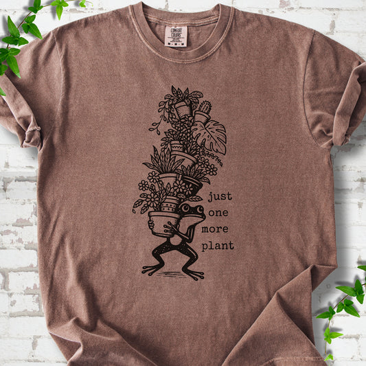 Espresso Comfort Colors® T-shirt flat lay featuring a frog carrying a tall stack of houseplants and the words just one more plant.