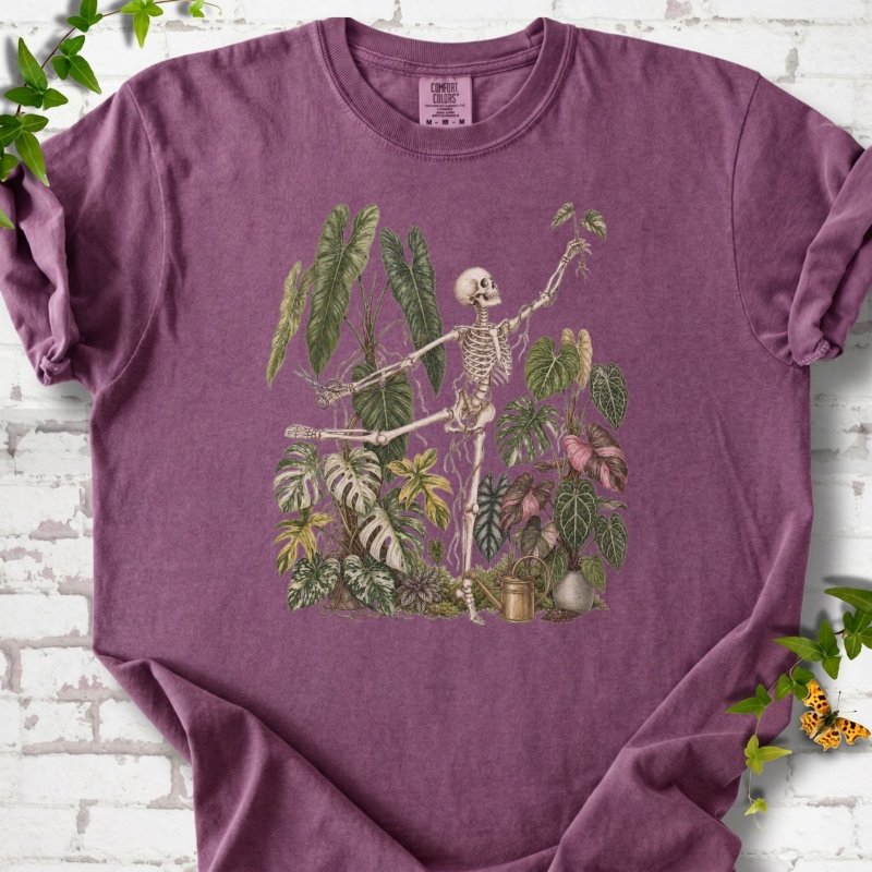 Berry Comfort Colors® T-shirt front mockup featuring a skeleton tending a collection of leafy houseplants.