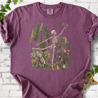 Berry Comfort Colors® T-shirt front mockup featuring a skeleton tending a collection of leafy houseplants.