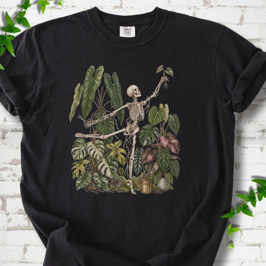 Black Comfort Colors® T-shirt front mockup featuring a skeleton tending a collection of leafy houseplants.