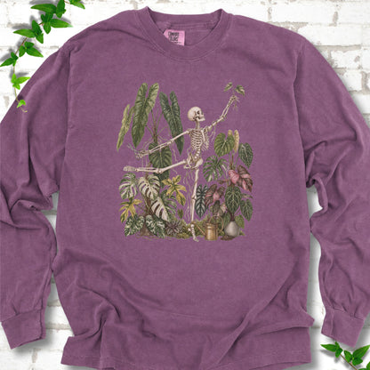 Berry Comfort Colors® long sleeve T-shirt front mockup featuring a skeleton tending a collection of leafy houseplants.