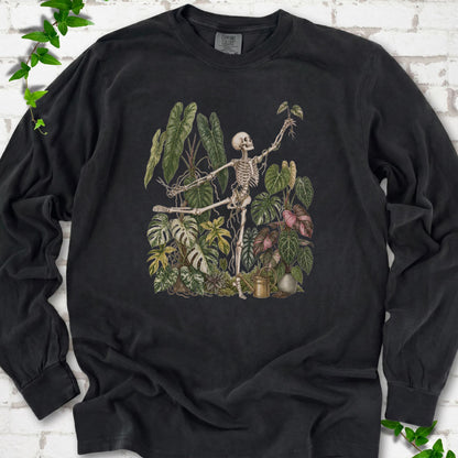 Black Comfort Colors® long sleeve T-shirt front mockup featuring a skeleton tending a collection of leafy houseplants.