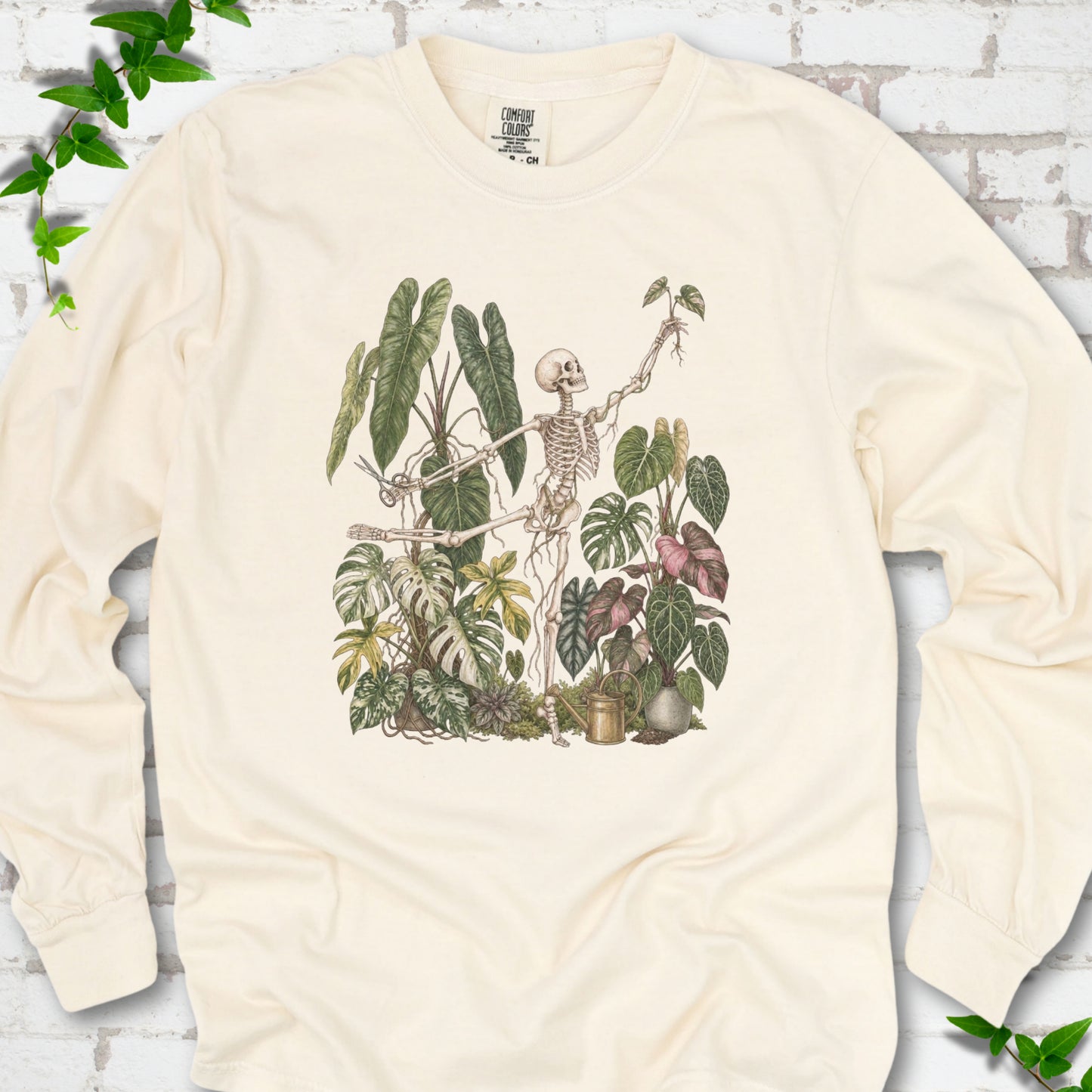 Ivory Comfort Colors® long sleeve T-shirt front mockup featuring a skeleton tending a collection of leafy houseplants.