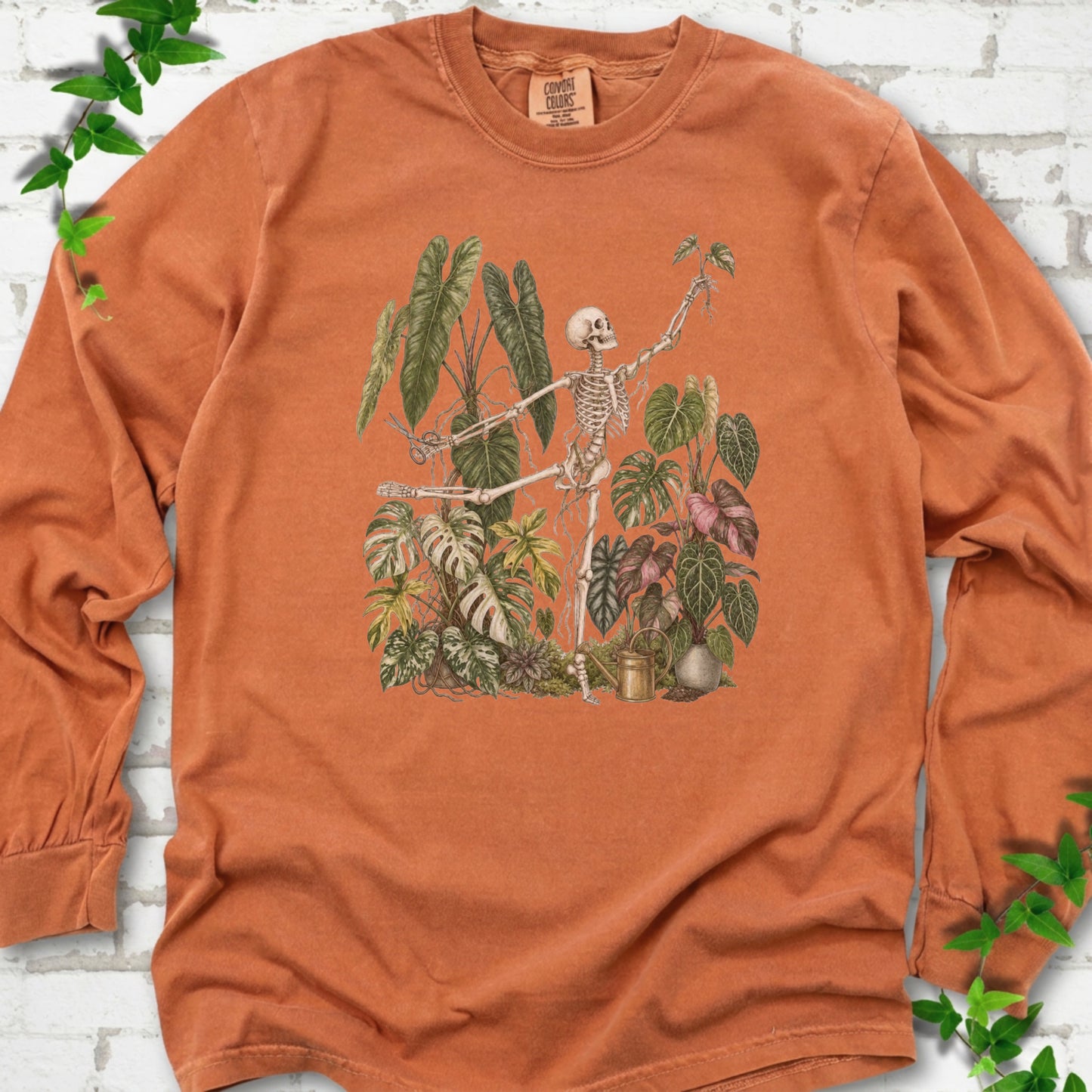 Yam Comfort Colors® long sleeve T-shirt front mockup featuring a skeleton tending a collection of leafy houseplants.