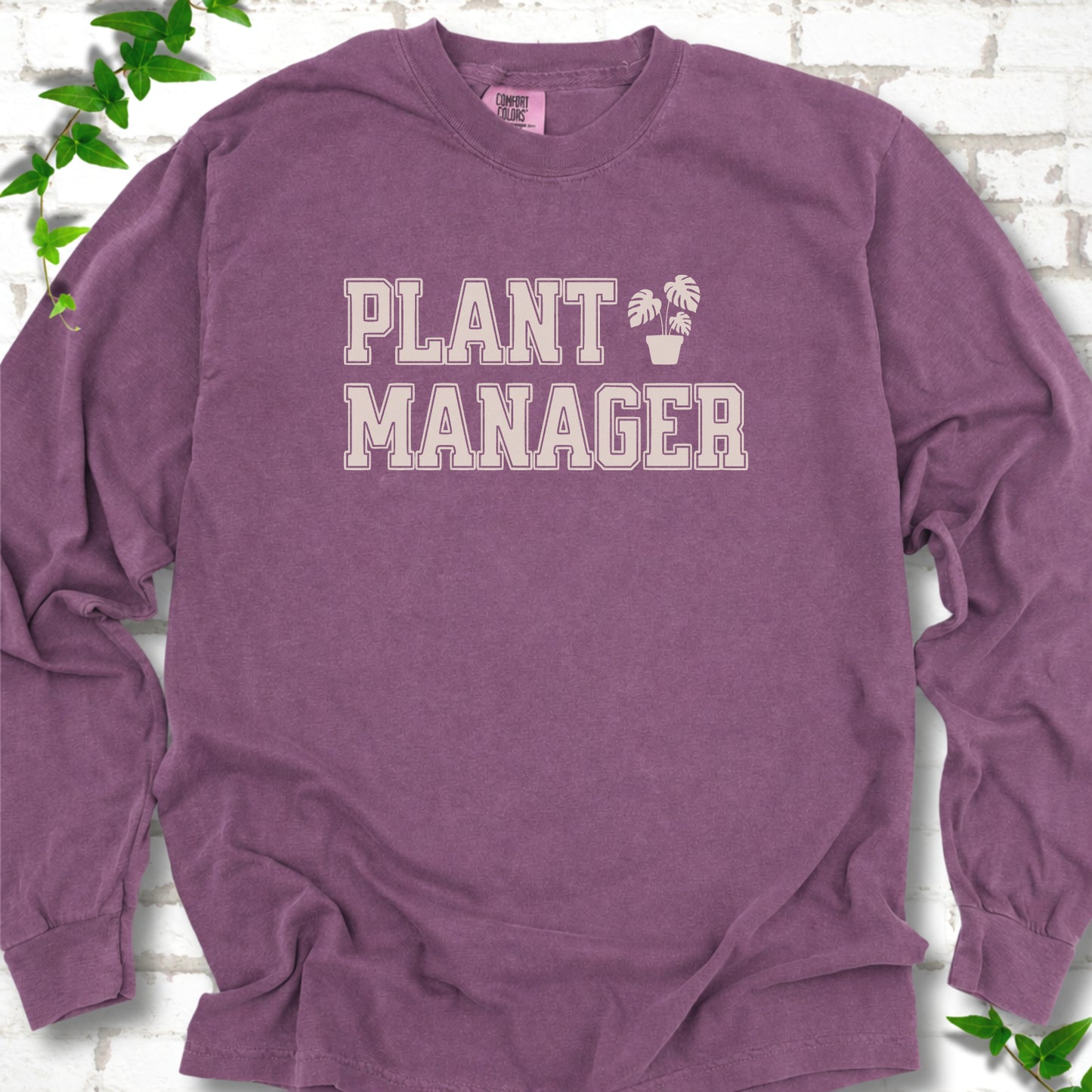 Berry Comfort Colors® long sleeve T-shirt front mockup featuring the collegiate Plant Manager design with a potted monstera.