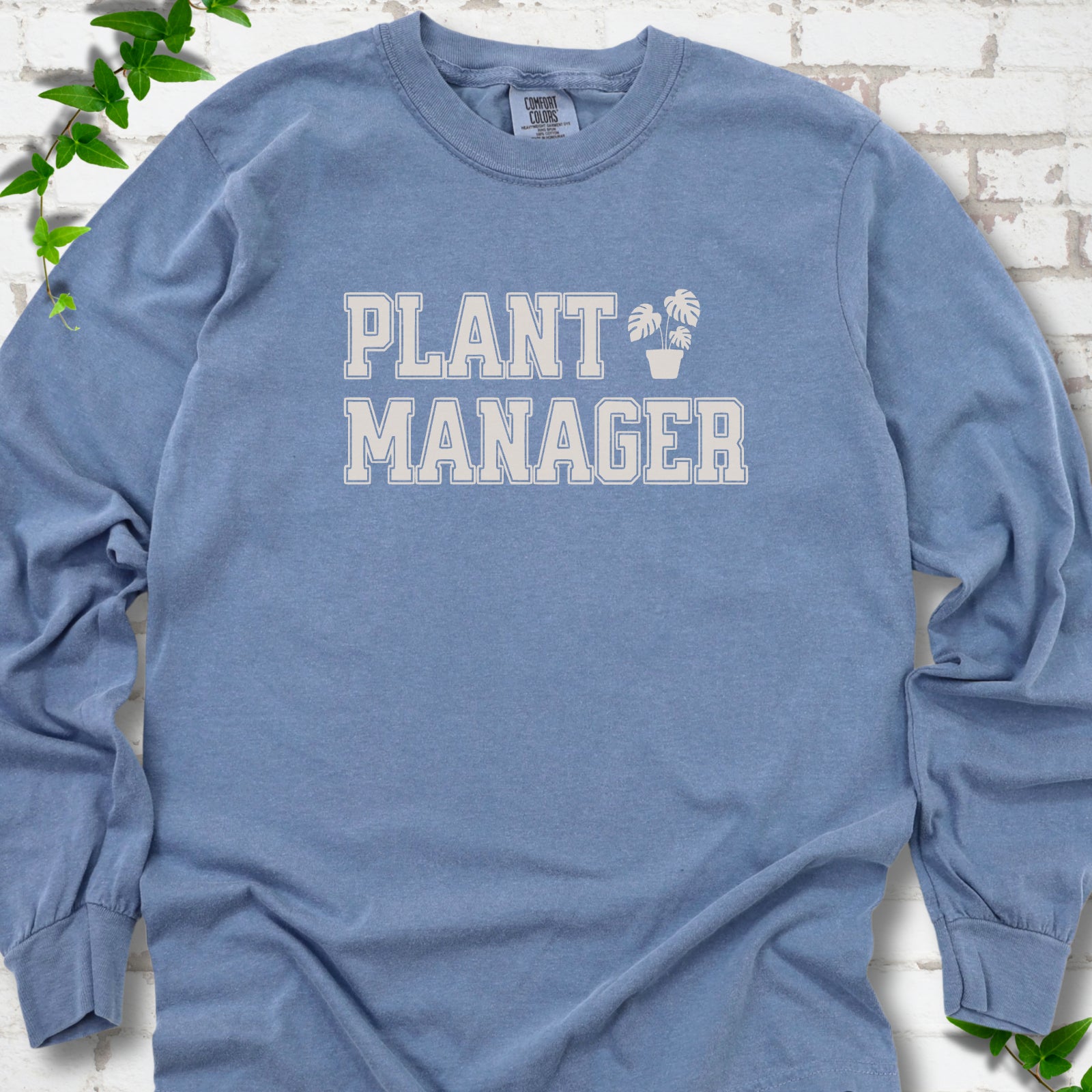 Blue Jean Comfort Colors® long sleeve T-shirt front mockup featuring the collegiate Plant Manager design with a potted monstera.