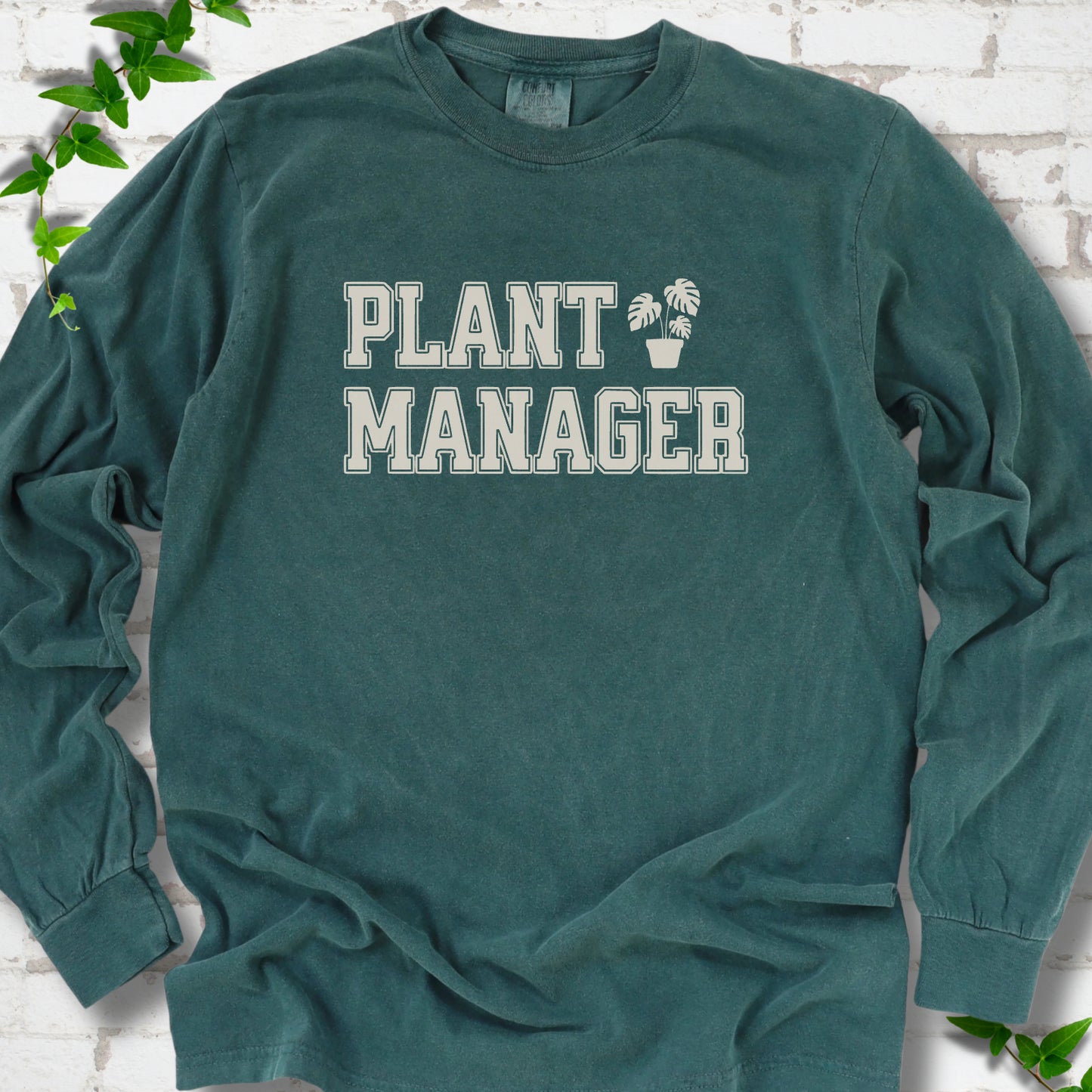 Blue Spruce Comfort Colors® long sleeve T-shirt front mockup featuring the collegiate Plant Manager design with a potted monstera.