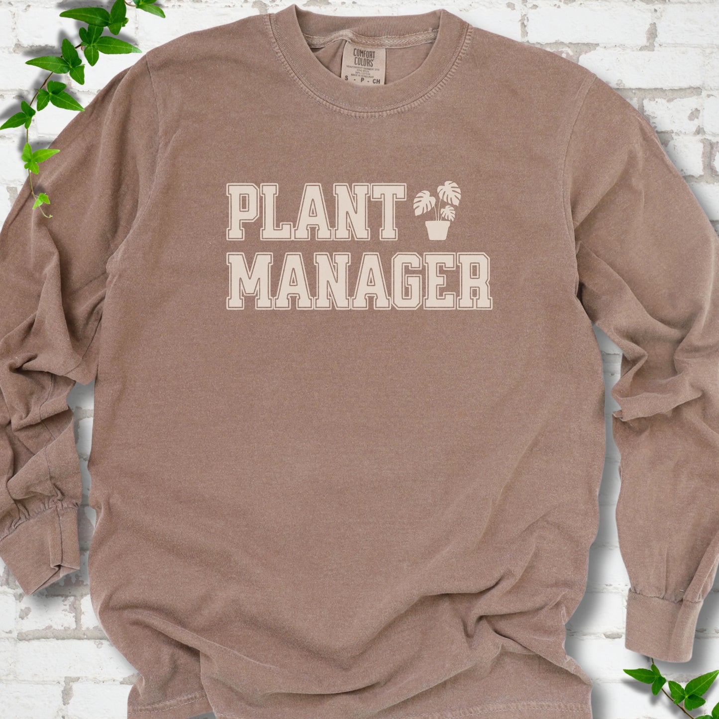 Espresso Comfort Colors® long sleeve T-shirt front mockup featuring the collegiate Plant Manager design with a potted monstera.