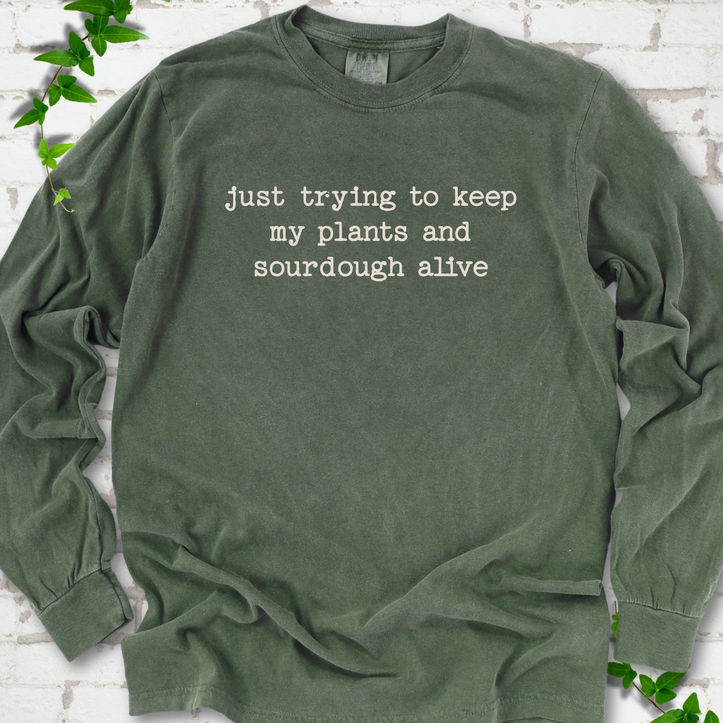 Hemp Comfort Colors® long sleeve T-shirt front mockup featuring the words “just trying to keep my plants and sourdough alive.”