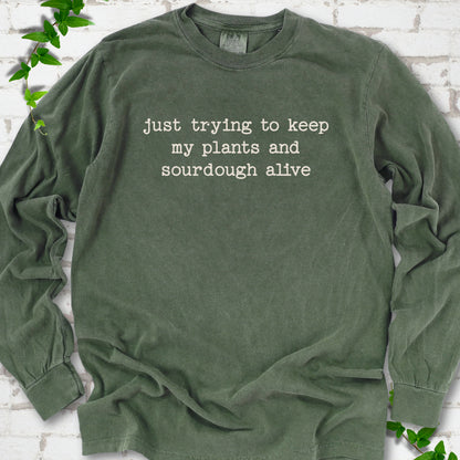 Hemp Comfort Colors® long sleeve T-shirt front mockup featuring the words “just trying to keep my plants and sourdough alive.”