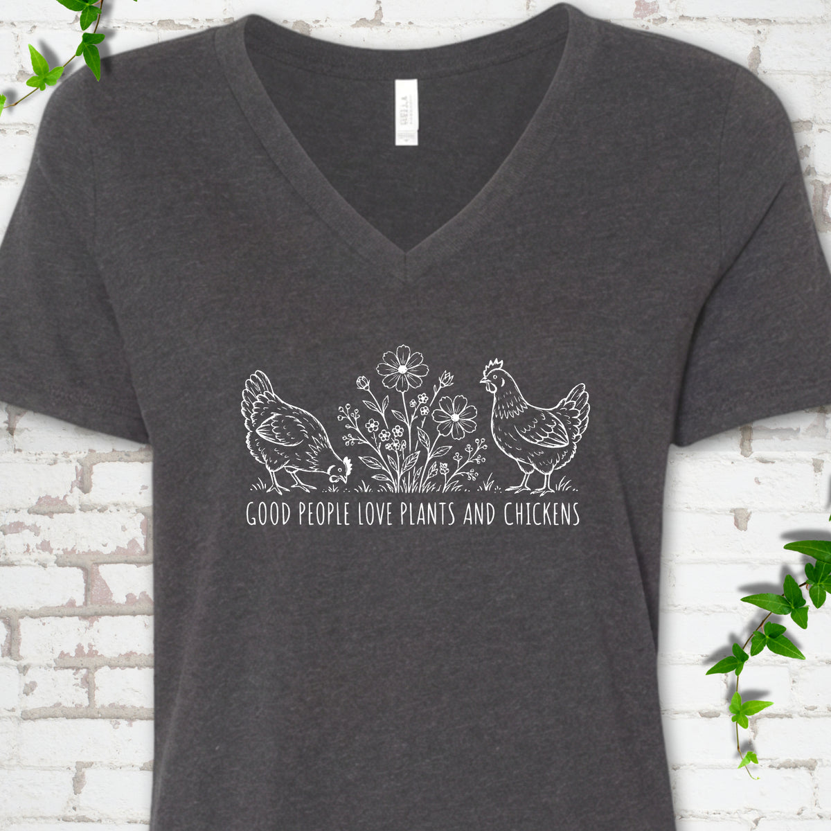 Dark Grey Heather women's V-neck T-shirt flat lay with white line-art hens and flowers above the words "Good People Love Plants and Chickens."