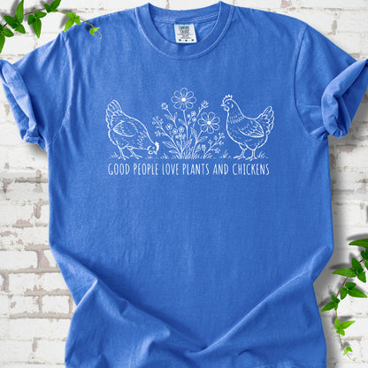Flo Blue T-shirt flat lay with white line-art hens and flowers above the words "Good People Love Plants and Chickens."