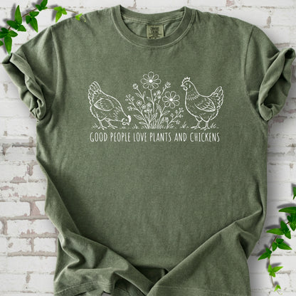 Moss T-shirt flat lay with white line-art hens and flowers above the words "Good People Love Plants and Chickens."