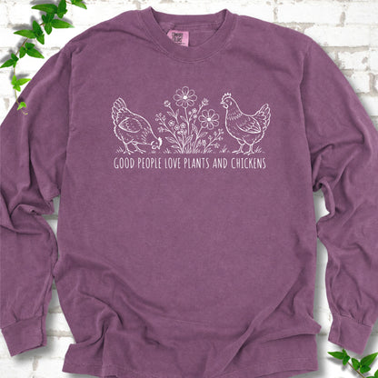 Berry long-sleeve T-shirt flat lay with white line-art hens and flowers above the words "Good People Love Plants and Chickens."
