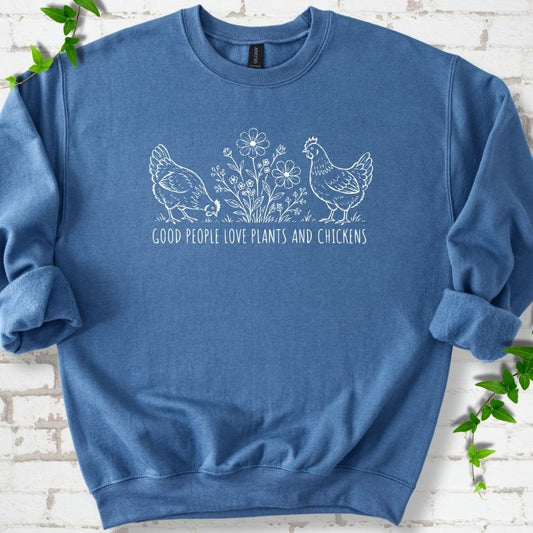 Indigo Blue crewneck sweatshirt flat lay with white line-art hens and flowers above the words "Good People Love Plants and Chickens."