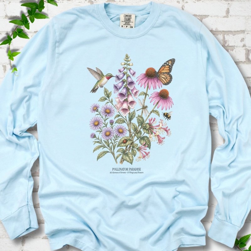 Chambray Comfort Colors® long sleeve T-shirt flat lay featuring a hummingbird, monarch butterfly and bee among foxglove, coneflowers and asters with Pollinator Paradise text.
