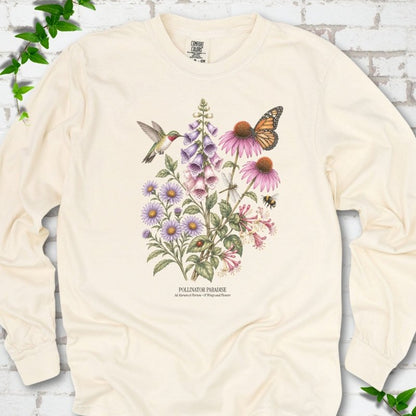 Ivory Comfort Colors® long sleeve T-shirt flat lay featuring a hummingbird, monarch butterfly and bee among foxglove, coneflowers and asters with Pollinator Paradise text.