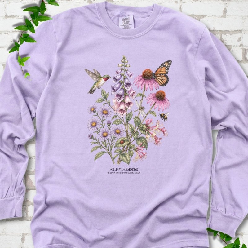 Violet Comfort Colors® long sleeve T-shirt flat lay featuring a hummingbird, monarch butterfly and bee among foxglove, coneflowers and asters with Pollinator Paradise text.
